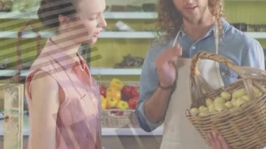 Animation of data processing over happy caucasian male greengrocer and female customer in shop. Fresh vegan food, plant based diet, healthy eating concept digitally generated video.