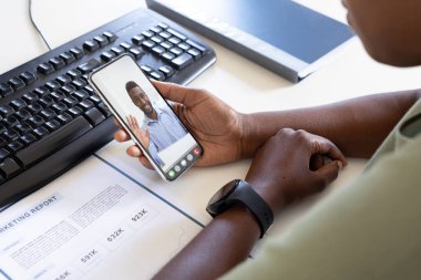 Afrikalı Amerikalı iş adamı, video görüşmesi sırasında Afrikalı Amerikalı erkek meslektaşına el sallıyor. Değiştirilmemiş iş, kablosuz teknoloji, toplantı, çalışma, takım çalışması ve ofis konsepti.