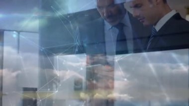 Network of connections over two caucasian businessmen using digital tablet against clouds in the sky. global networking and business data storage technology concept