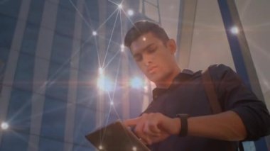 Glowing network of connections against biracial man using digital tablet. global networking and business technology concept