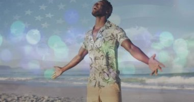 Spots of light against african american man with arms wide open enjoying on the beach. Travel and vacation concept