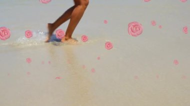 Sahilde yürüyen bir kadının düşük kesimine düşen birden fazla pembe gül ikonu. Seyahat ve tatil kavramı