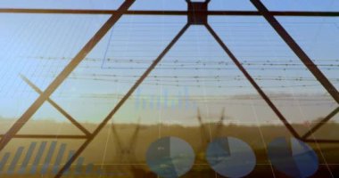 Günbatımında elektrik direkleri üzerinden finansal grafiklerin ve verilerin animasyonu. Dijital olarak üretilen enerji, elektrik, finans ve ekonomi konsepti.