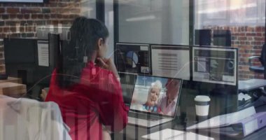 Animation of financial graphs over biracial woman having video call in office. Business, communication and technology concept digitally generated video.