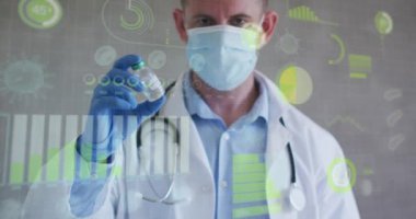 Virüs hücrelerinin animasyonu ve beyaz erkek doktorun elinde aşı olan yüz maskesi üzerindeki veriler. Sağlık, ilaç ve covid 19 salgın konsepti dijital olarak oluşturulmuş video.