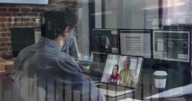 Animation of financial graphs over caucasian man in face mask having video call in office. Business, communication, technology and covdi 19 pandemic concept digitally generated video.