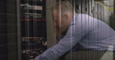Caucasian senior male engineer talking on smartphone while working in computer server room. Cyber security and business data storage technology concept