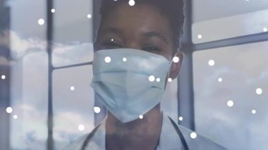 Beyaz lekeler, yüz maskesi takan Afro-Amerikan kadın doktor portresinin üzerine düşüyor. Tıbbi sağlık hizmeti kavramı