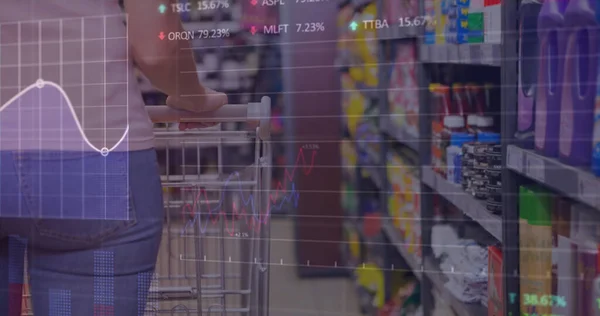 Image of data processing over caucasian woman with trolley in shop. global business, shopping and digital interface concept digitally generated image.