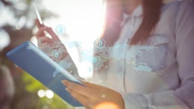 Dijital tablet kullanan bir kadının orta kesimine karşı dünya haritasında birden fazla bitcoin sembolü var. Küresel ağ ve teknoloji kavramı