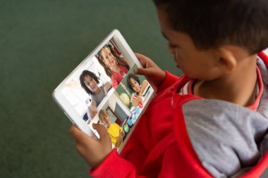 Çevrimiçi derste dijital tablet ekrana bakan melez çocuğun yüksek açılı görüntüsü. Değiştirilmemiş, çocukluk, kablosuz teknoloji, eğitim, öğrenci ve e-öğrenim kavramı.