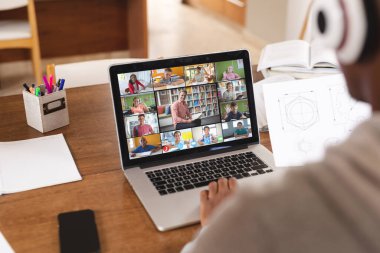 Diz üstü bilgisayar ekranına bakan çok ırklı bir çocuk ve erkek öğretmen online sınıfta öğrencilere ders veriyor. Değiştirilmemiş, çocukluk, kablosuz teknoloji, eğitim, internet, video çağrısı ve e-öğrenme kavramı.
