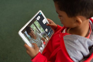 Çevrimiçi sınıfta dijital tablet ekranda öğretmenine bakan melez bir çocuğun yüksek açılı görüntüsü. İnternet, ev, değiştirilmemiş, çocukluk, kablosuz teknoloji, eğitim, öğrenci ve e-öğrenim.