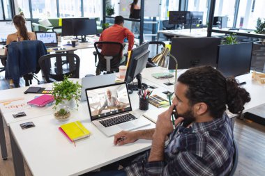 Çift ırklı iş adamı, iş kadınıyla modern ofiste dizüstü bilgisayarla konuşuyor. Değiştirilmemiş, çevrimiçi, teknoloji, video konferansı, İnternet, iş dünyası, takım çalışması.