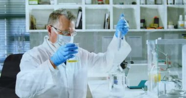 Kafkas kıdemli erkek laboratuvar çalışanı üzerinde yüz maskesi ve numuneyle kimyasal formüllerin canlandırılması. Bilim, kimya ve tıp konsepti dijital olarak üretilen video.