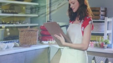 Animation of financial graphs over happy caucasian female seller in grocery shop. economy, finance, shopping and small independent business concept digitally generated video.
