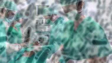 Animation of covid 19 cells over diverse surgeons wearing face masks in operating theatre. global covid 19 pandemic, medicine and healthcare services concept digitally generated video.