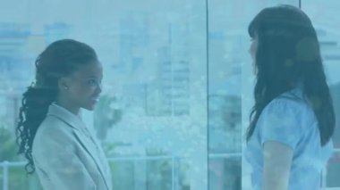 Animation of dots floating over diverse female doctors shaking hands. Health, medicine and cooperation concept digitally generated video.