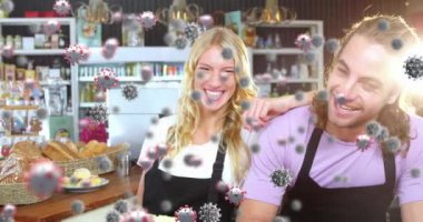 Animation of virus cells over happy caucasian female and male waiters. business and covid 19 pandemic concept digitally generated video.