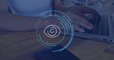 Animation of eye icon over caucasian businesswoman using laptop in office. Global business and digital interface concept digitally generated video.