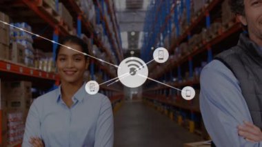 Animation of network of connections with icons over happy diverse warehouse workers. business, connections, technology and delivery services concept digitally generated video.