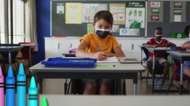Yüzü maskeli okul çocukları üzerine renkli kalemlerin animasyonu. Küresel eğitim ve dijital arayüz kavramı dijital olarak oluşturulmuş video.