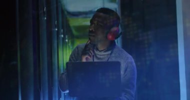 Sunucu odasında kulaklık takan Afro-Amerikan bir adamın Bitcoin şarkılarının animasyonu. Bulut hesaplama, dijital arayüz ve güvenlik konsepti dijital olarak oluşturulmuş video.