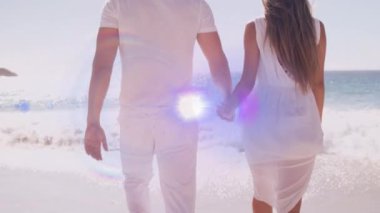 Animation of light moving over back view of caucasian newly married couple on beach. love, relationship and emotions concept digitally generated video.