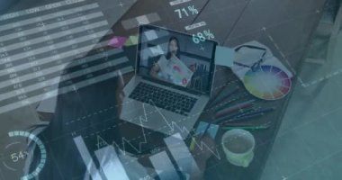 Animation of financial graphs and data over african american female designer having video call. economy, finance and business concept digitally generated video.
