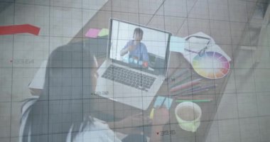 Animation of financial graphs and data over african american female designer having video call. economy, finance and business concept digitally generated video.