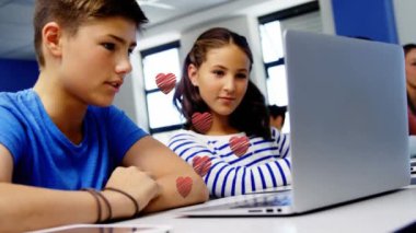 Multiple red heart icons over caucasian boy and girl using laptop at school. School and education concept