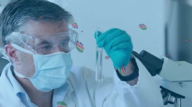 Animation of balls falling over caucasian male lab worker using microscope. Animation of dots floating over biracial female lab worker using microscope.