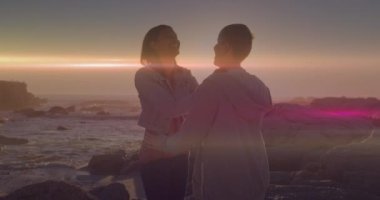 Kumsaldaki beyaz bir çiftin üzerinde ışıklı noktaların canlandırılması. Tatiller ve dijital arayüz kavramı dijital olarak oluşturulmuş video.