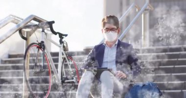 Merdivenlerde oturan yüz maskesi takan Asyalı adama karşı yüzen çoklu covid-19 hücreleri. Covid-19 salgın konsepti