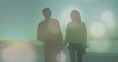 Kumsaldaki beyaz bir çiftin üzerinde ışıklı noktaların canlandırılması. Tatiller ve dijital arayüz kavramı dijital olarak oluşturulmuş video.