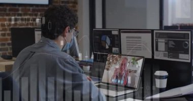 Data processing over caucasian man wearing a face mask having a video call on laptop at office. Business analytics and data technology concept