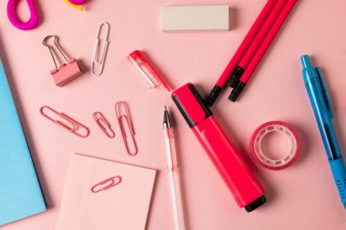 Pembe ve kırmızı okul ekipmanları, klipsli ve açık pembe yüzeye bantlı. Okul ekipmanları, araçlar ve yaratıcılık kavramı.