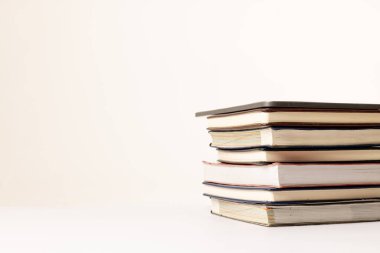 Bej yüzey üzerine kitap yığını görüntüsü. Okul ekipmanları, araçlar, öğrenme ve yaratıcılık kavramı.