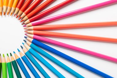 Beyaz yüzeydeki renkli pastel boyaların merkezi bileşimi. Okul ekipmanları, çizim araçları, şablon ve yaratıcılık kavramı.