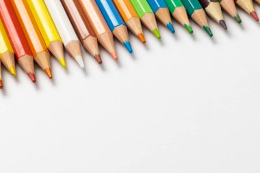 Beyaz yüzeyde fotokopi alanı olan renkli boya kalemlerinin bileşimi. Okul ekipmanları, çizim araçları ve yaratıcılık kavramı.