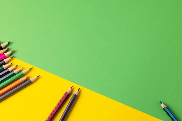 Composition of colorful crayons on yellow and green surface with copy space. School equipment, drawing tools, pattern and creativity concept.