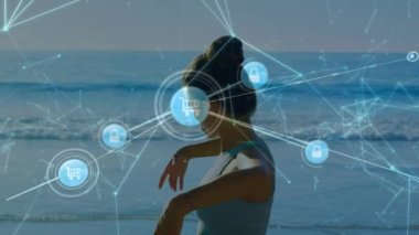 Animation of network of connections with icons over biracial woman exercising on the beach. Global connections, data processing and digital interface concept digitally generated video.