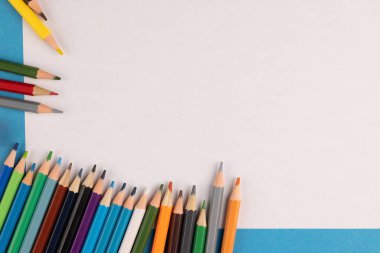 Image of colorful crayons white sheet of paper on blue background. Education, learning and creativity.