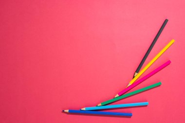 Pembe yüzeyde fotokopi alanı olan renkli boya kalemlerinin bileşimi. Okul ekipmanları, çizim araçları ve yaratıcılık kavramı.