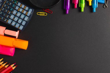 Siyah yüzey üzerindeki renkli okul araçlarının kompozisyonu ve fotokopi alanı. Okul ekipmanları, araçlar ve yaratıcılık kavramı.