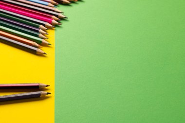 Sarı ve yeşil yüzeydeki renkli boya kalemlerinin kompozisyonu. Okul ekipmanları, çizim araçları, şablon ve yaratıcılık kavramı.