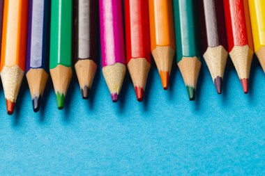 Mavi yüzeyde fotokopi alanı olan renkli boya kalemlerinin bileşimi. Okul ekipmanları, çizim araçları, şablon ve yaratıcılık kavramı.