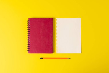 Sarı yüzeyinde kopya alanı ve kalem olan defterlerin bileşimi. Okul ekipmanları, araçlar, eğitim ve yaratıcılık kavramı.