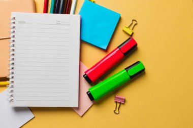 Composition of notebook with copy space and school equipment on yellow surface. School equipment, tools and creativity concept.