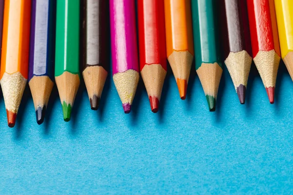 Mavi yüzeyde fotokopi alanı olan renkli boya kalemlerinin bileşimi. Okul ekipmanları, çizim araçları, şablon ve yaratıcılık kavramı.